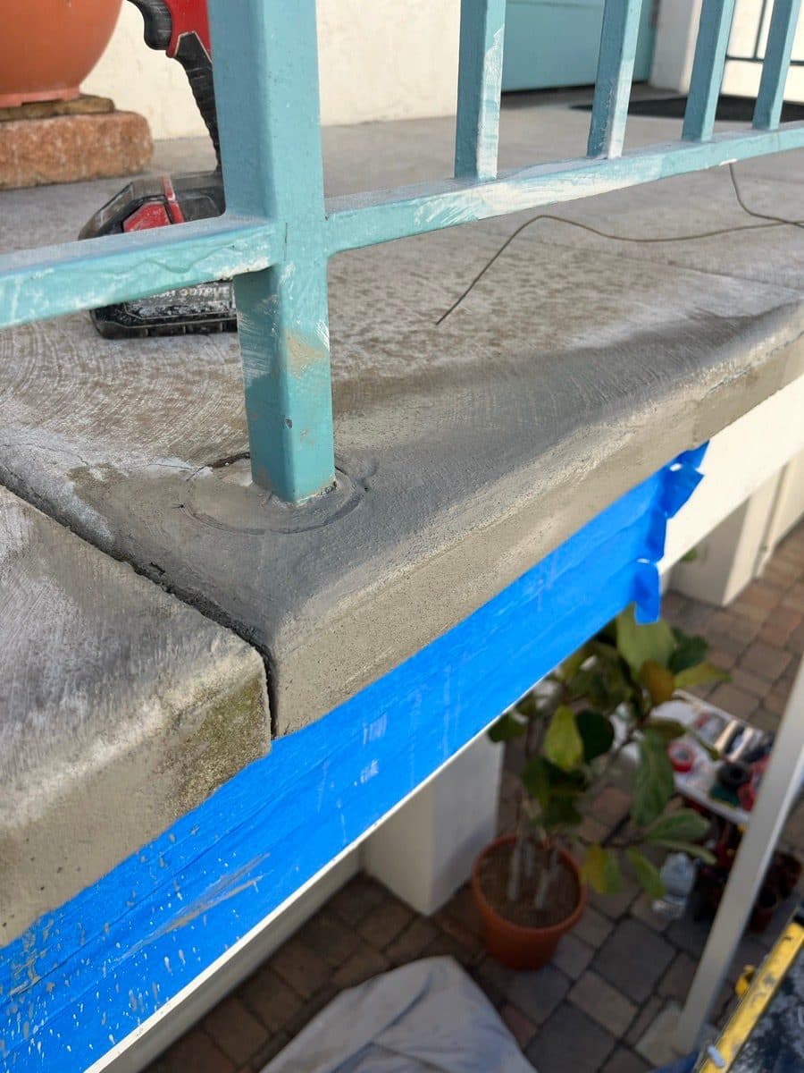 Patched balcony concrete edge around a railing post after repair